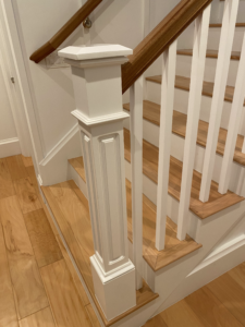 the bottom of a wooden white staircase